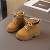 A pair of tan kids' winter leather boots with laces and a brown cuff resting on a gray surface.