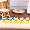 Five miniature resin wine bottles and cups filled with yellow liquid arranged on a wooden surface.