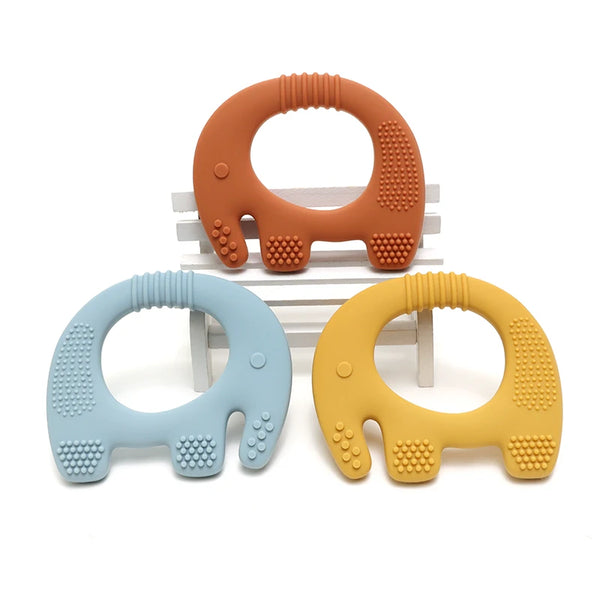 Two silicone elephant teethers in orange and yellow are displayed on a wooden surface.