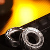 A close-up of a silver magnetic fidget ring with an adjustable wheel resting on a dark surface.