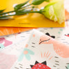 A close-up of a fabric with a dinosaur grid print featuring pink, green, and orange elements.
