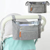 A gray fabric organizer bag with hanging hooks is shown attached to a stroller bar.