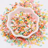 A white bowl filled with colorful polymer clay sprinkles mix for slime decor and DIY craft accents scattered on a white surfa