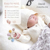A newborn baby is sleeping peacefully while holding a silicone baby teether with chew beads.