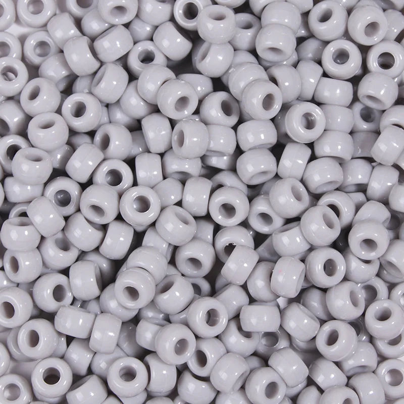 A close-up view of a 100-pack of small, round, white pony beads for jewelry making and craft projects.