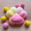 A pink and yellow mochi squishy fidget toy shaped like a cat paw, made of soft, fluffy material.
