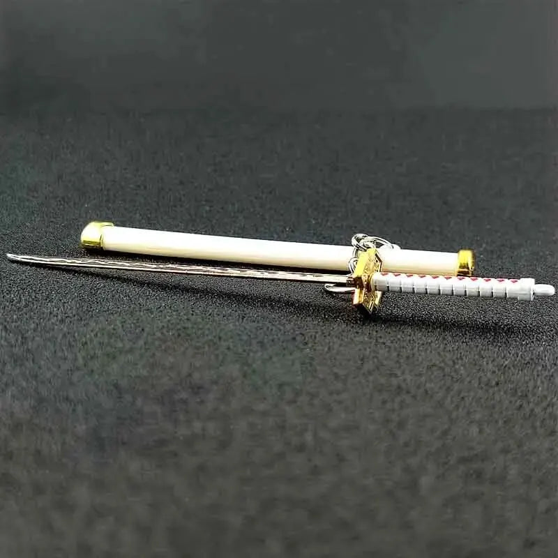 A samurai sword keychain featuring a white blade and gold accents resting on a dark surface.