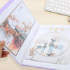 A transparent diamond painting storage album showing a detailed floral scene and a deer illustration.