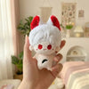 A hand holds a white and red fluffy anime plush keychain charm against a light background.