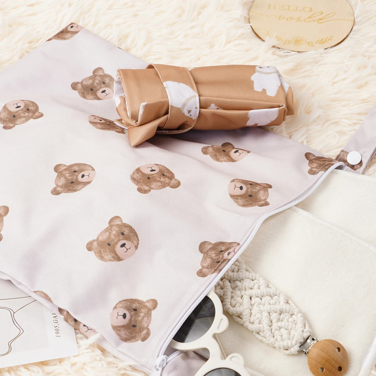 A set of two reusable waterproof baby wet bags featuring a light beige color and bear print on a fluffy white background.