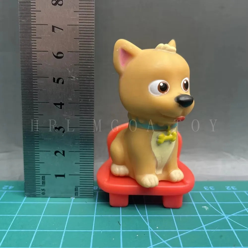 A yellow cartoon figurine resembling a dog wearing a collar, sitting on a red stool, next to a ruler.