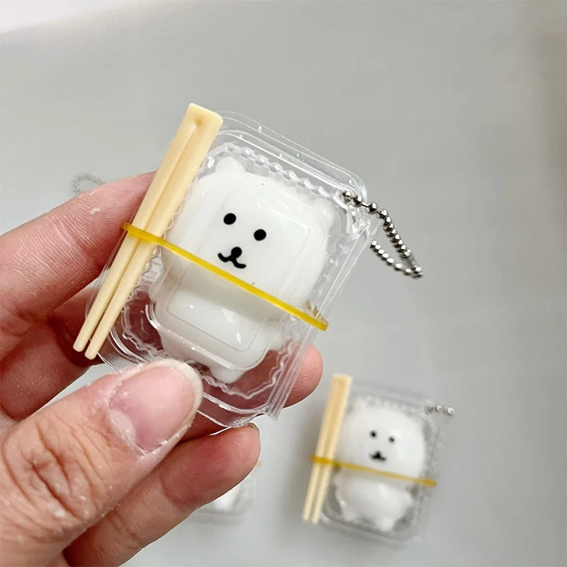 A hand holds a clear plastic package containing a white Hachiware Usagi squishy stress relief toy with yellow accents.