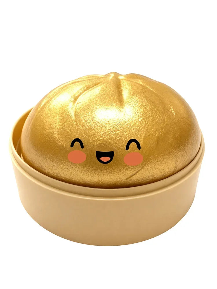 A golden, round squishy toy shaped like a dumpling with cute facial features resting in a light beige container.
