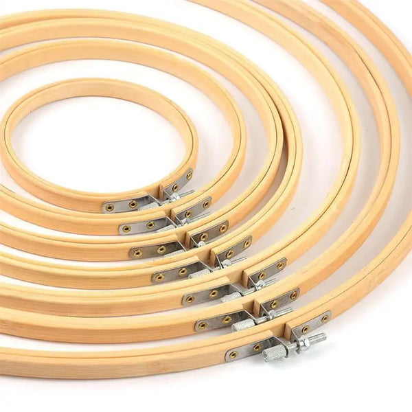 Several light wood bamboo embroidery hoops are arranged in a fan shape for needlecraft.