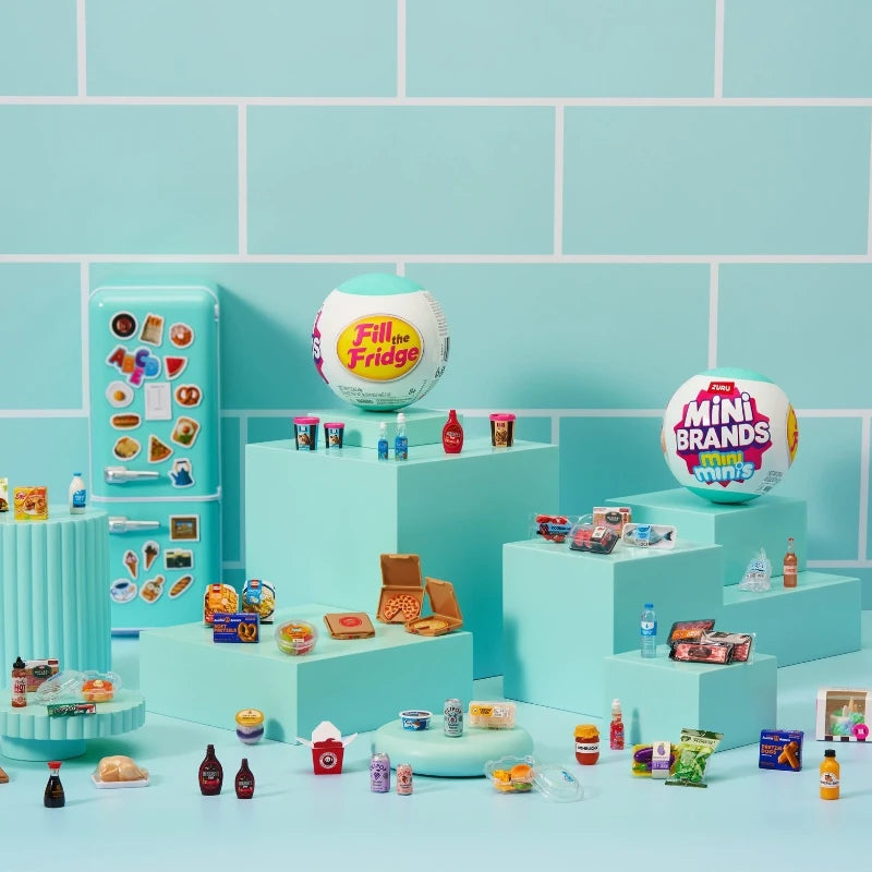 A collection of Mini Brands Mystery Balls and related items displayed on a light blue surface against a teal tiled background