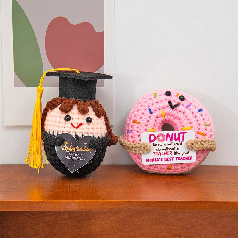 A handmade crochet graduation gift featuring a black felted owl with a graduation cap and a pink donut with an inspirational 