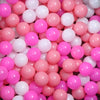 A close-up view of a large pack of colorful plastic balls in various shades of pink and white.