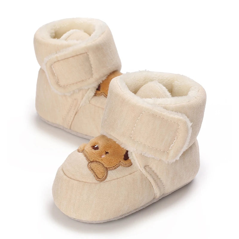 A pair of light beige baby winter cartoon boots with soft faux fur trim and a non-slip sole.