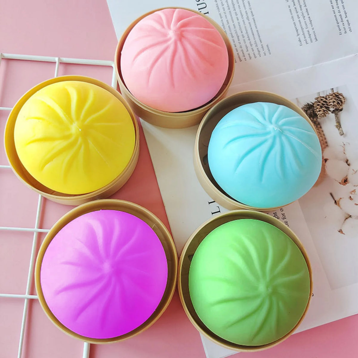 A collection of five brightly colored squishy stress balls in various shades including pink, yellow, blue, and green, display
