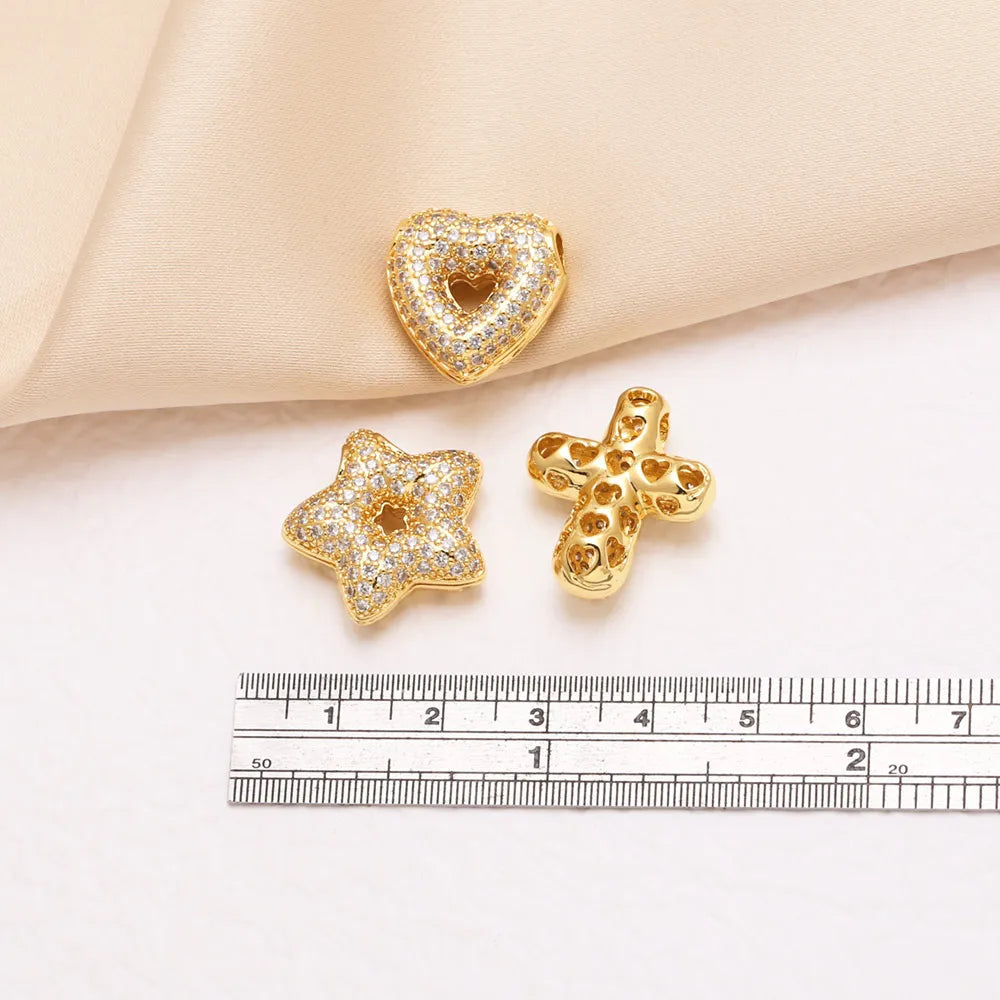 Gold tone crystal heart cross pendant resting on a white surface next to a ruler.