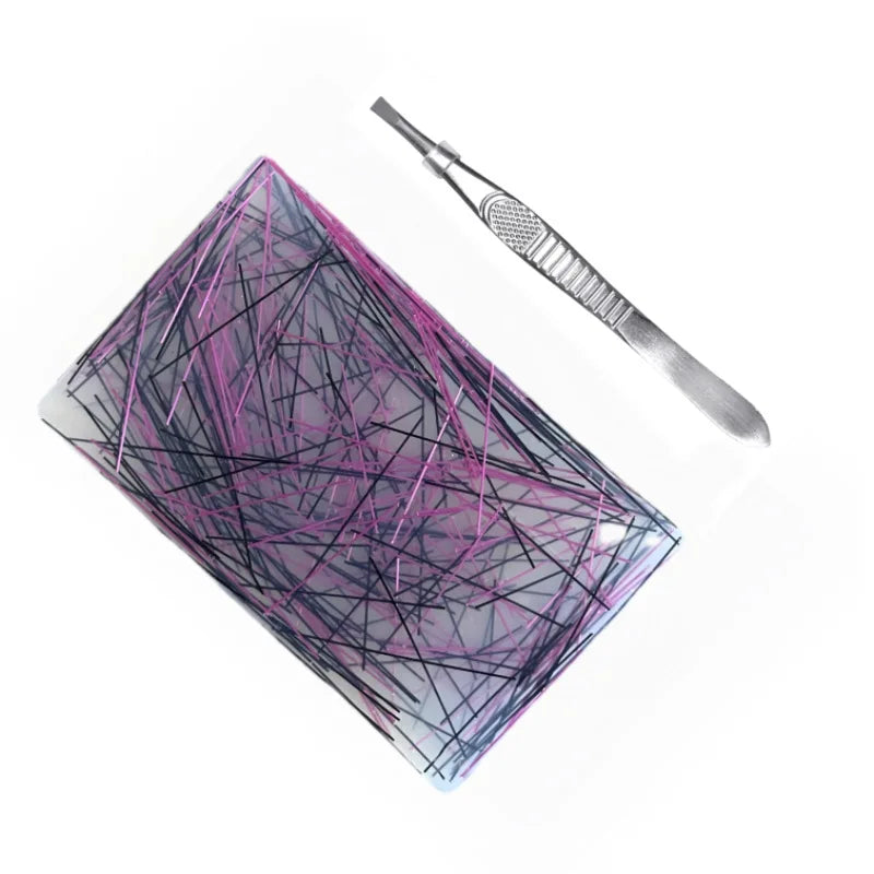Silikonisches Sensorspielzeug mit rosa und schwarzen Linien neben einem Metallwerkzeug.