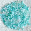 A pile of light blue and clear acrylic bow and flower beads for DIY jewelry making