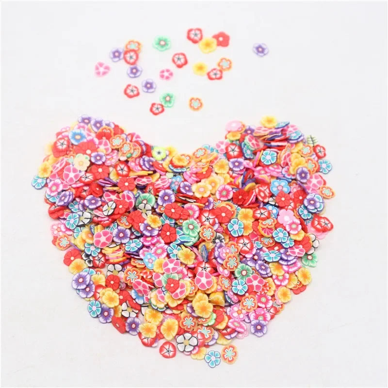 A heart shape made of colorful polymer clay flower charms scattered on a white background.