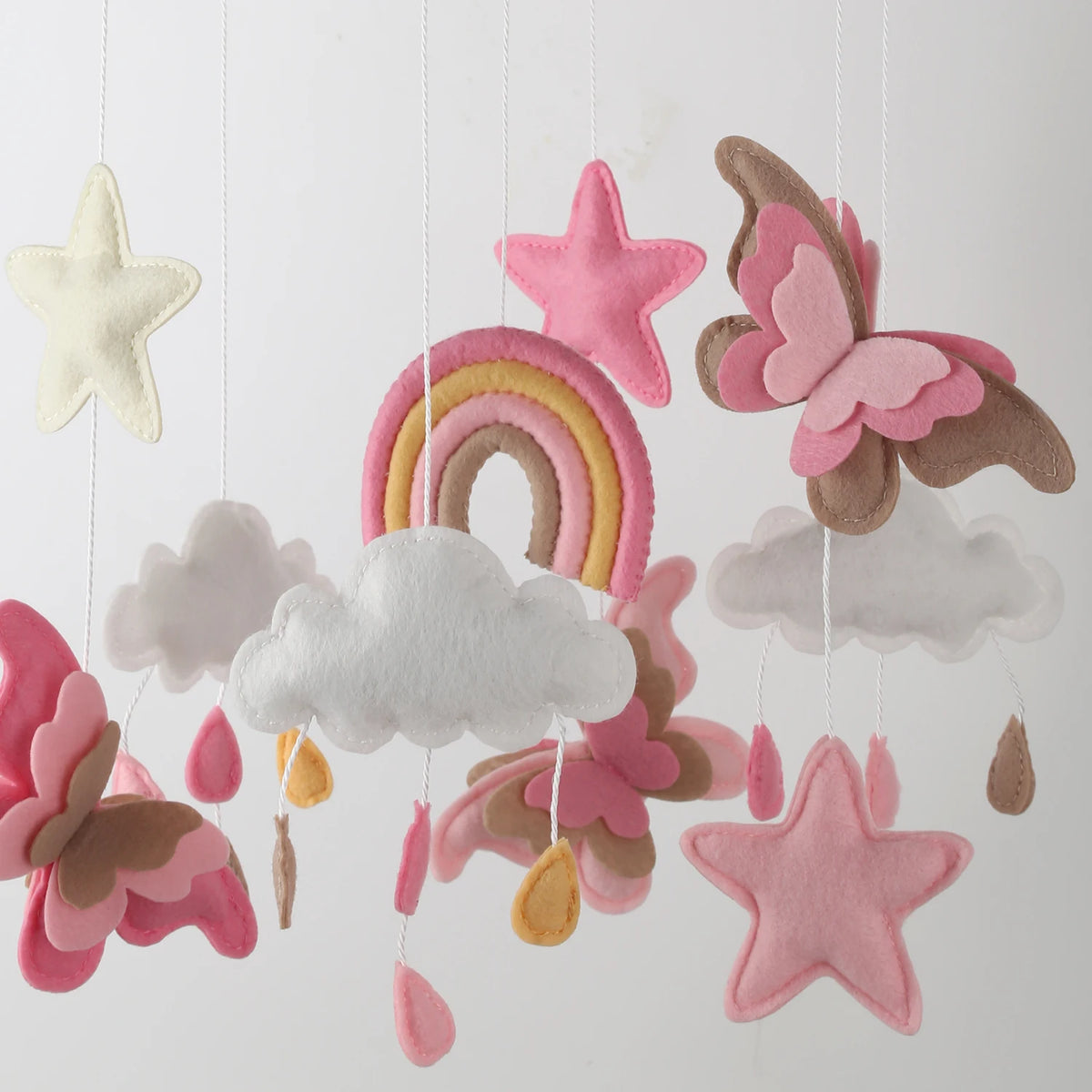 Handmade felt butterfly crib mobile featuring pink, beige, and gray stars and clouds