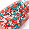 A hand holds a pile of polymer clay slices in various colors including red, orange, blue, and white.