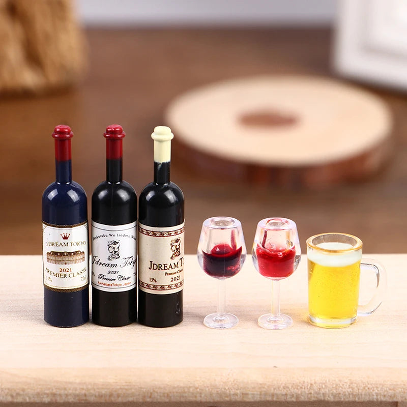 A set of five miniature resin wine bottles and glasses for a dollhouse display on a wooden surface.