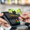 A hand holds a black card with a cat design against a dark electronic device.