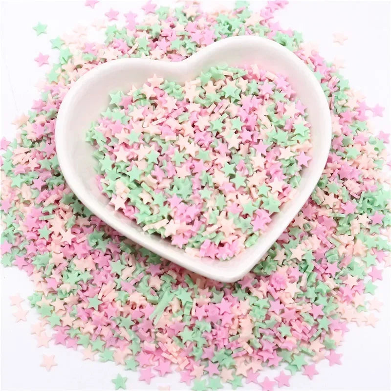 A heart-shaped dish filled with pink and green polymer clay sprinkles scattered on a white background.
