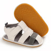 A pair of white and gray breathable baby first walker sandals with an orange anti-slip sole.