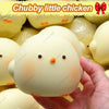 A hand holds a white chubby little chicken squishy toy with orange accents against a blurred background of similar toys.
