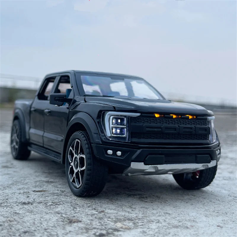 A black 1:20 scale Ford Raptor F150 diecast model truck parked on a gray surface.
