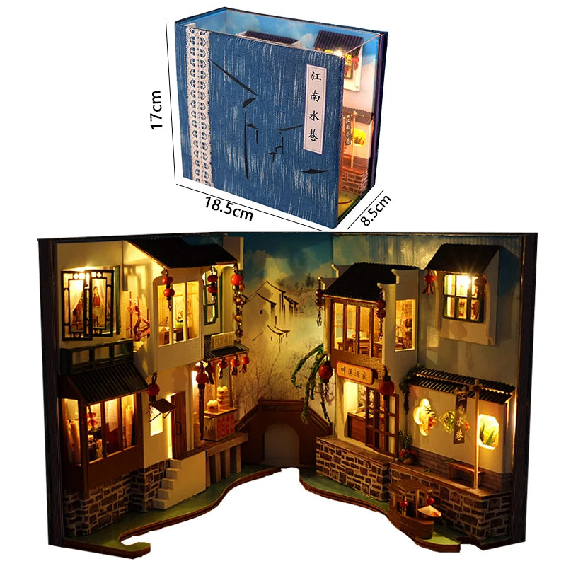 A wooden book nook kit featuring detailed miniature buildings and illuminated scenes.