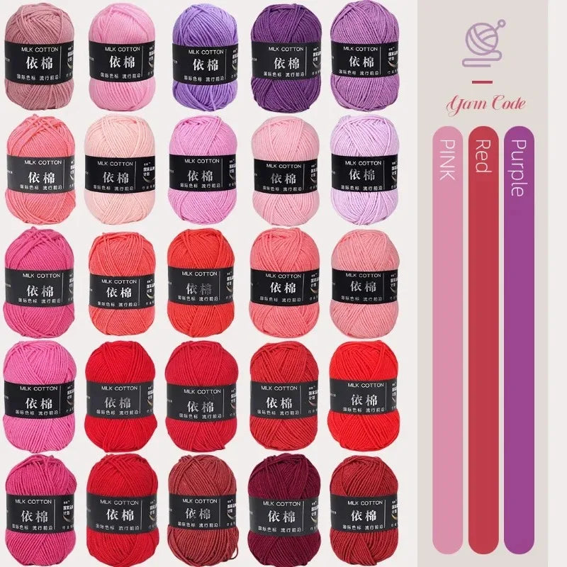 A collection of pink, red, and purple milk cotton yarn skeins for knitting and crochet projects.