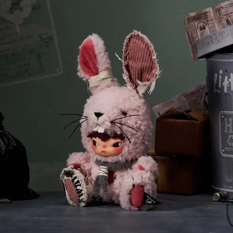 A fluffy pink rabbit plush doll with large ears and black whiskers sits on a dark surface.
