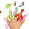 A hand holds a set of colorful rubber dinosaur slingshot toys, including green, blue, and red dinosaurs.