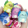 A hand holds several colorful squishy slow-rise stress relief toys shaped like cute newt figurines.