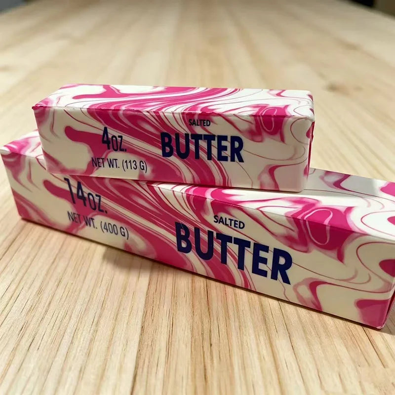 Two rectangular butter sticks with pink and white marbled patterns are displayed on a wooden surface.