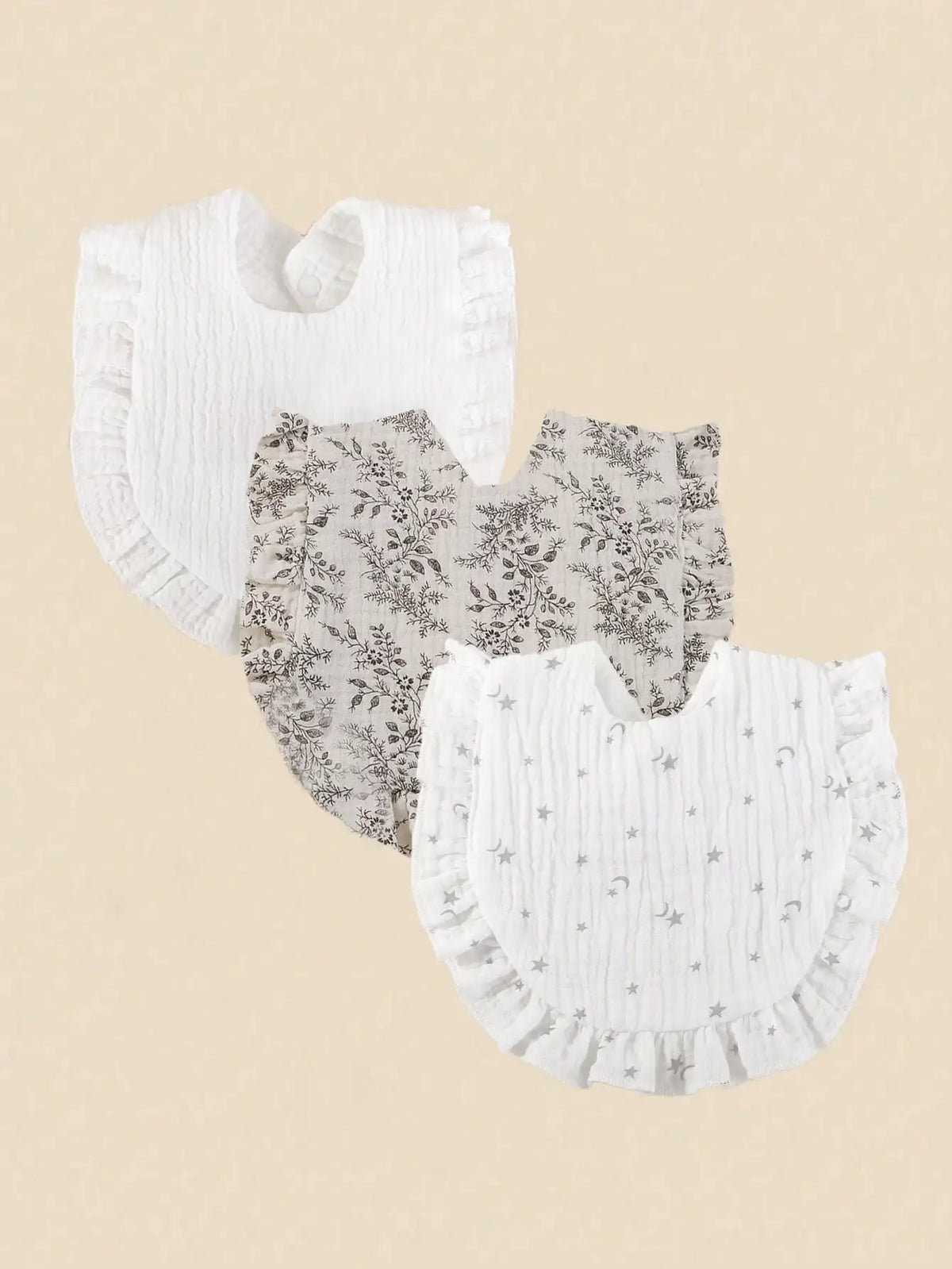 A set of three white cotton muslin baby bibs, featuring textured fabric and floral or star patterns.