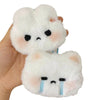 A white plush rabbit charm with black eyes and blue tear marks is held in a hand.
