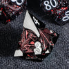 A close-up of a black and silver metal die featuring a dragon design and the number 3, set against a dark gray background.
