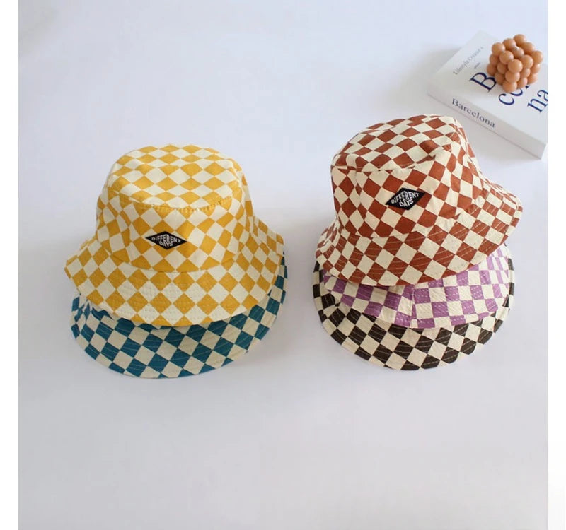 A collection of four bucket hats featuring different checkerboard patterns in yellow, brown, purple, and blue.