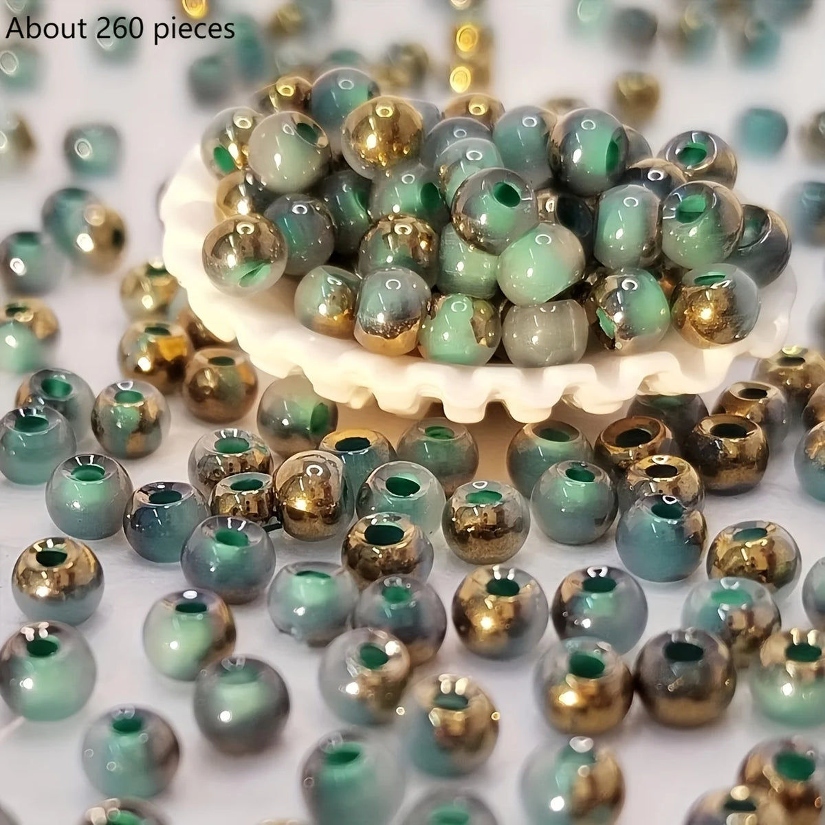 A pile of vibrant round beads in various shades of green and gold for jewelry making