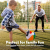 A young boy is tossing an inflatable beach ball outdoors while a man watches in the background.