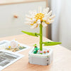 A green building block set shaped like a rose flower with white petals and a yellow center, resting on a wooden table.