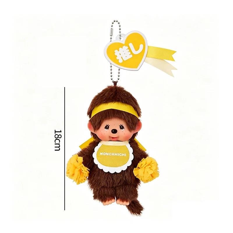A brown plush cartoon character with yellow accents and a heart-shaped charm featuring Japanese text.