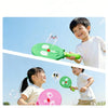 Two children are playing with a green smoke bubble wand outdoors under a clear blue sky.